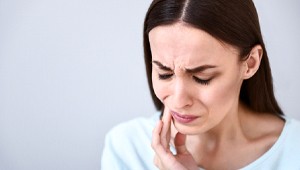 woman with tooth pain holding cheek
