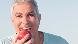 patient eating an apple and enjoying the benefits of All-on-X implants in Midland