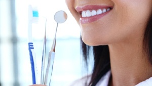 woman smiling holding dental tools