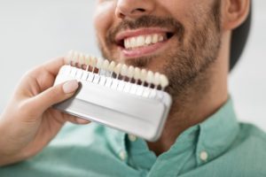man smiling with a dental assistant holding a color guide